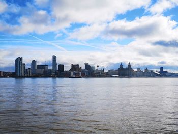 Scenic view of river by buildings against sky