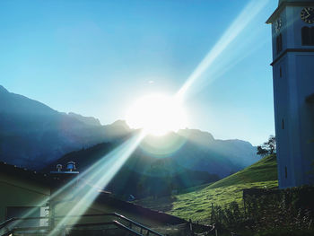 Sunlight streaming through mountain against sky on sunny day