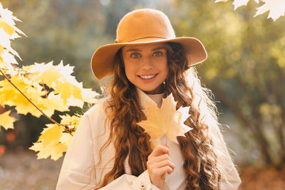 Young woman wearing hat standing against tree