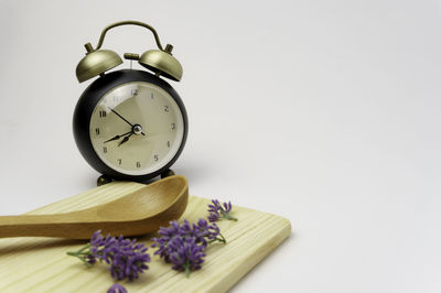 Close-up of clock on table against white background