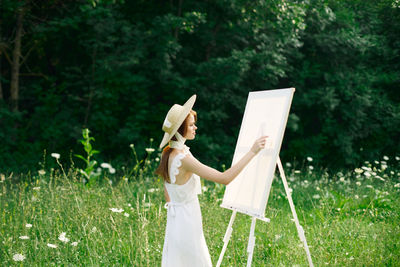 Woman holding umbrella while standing on field