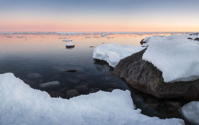 Close-up of snow on sea against sky during sunset