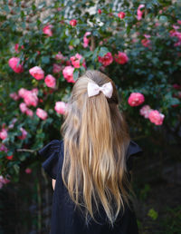 Rear view of woman standing by pink flowering plants