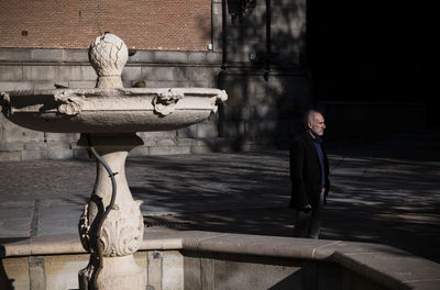 Adult man in suit standing on square with fountain