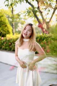 Portrait of young woman standing against trees