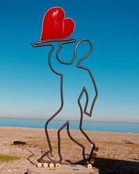 Red umbrella on beach against clear blue sky