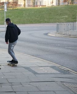 Full length of man skateboarding on street in city