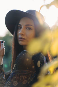 Portrait of young woman standing against blurred background