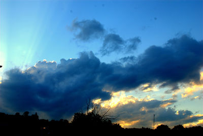 Silhouette of trees against cloudy sky