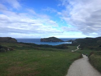 Scenic view of landscape by sea against sky