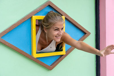 Portrait of smiling young woman against wall