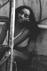 Woman with eyes closed sitting against wall