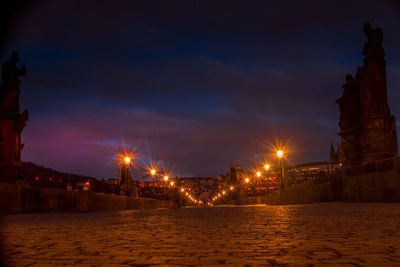 Illuminated city street by river at night