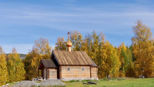 House amidst trees on field against sky