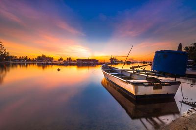 Boats in calm lake at sunset