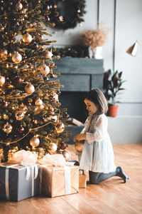 Side view of girl decorating christmas tree at home