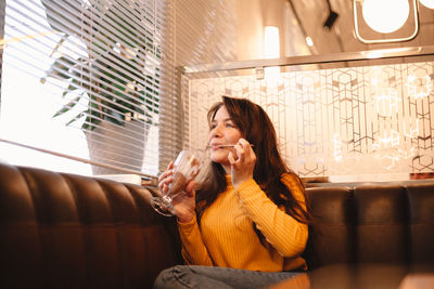 Happy teenage girl enjoying chocolate milkshake while sitting in cafe