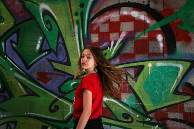 Full length of woman standing against graffiti wall