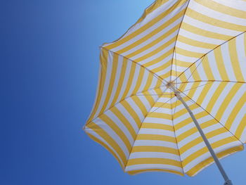 Low angle view of umbrella against clear blue sky