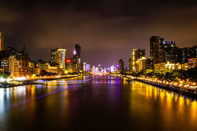 River amidst illuminated buildings against sky at night