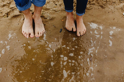 Low section of people standing on wet sand