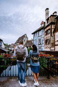 Rear view of friends standing against buildings in city