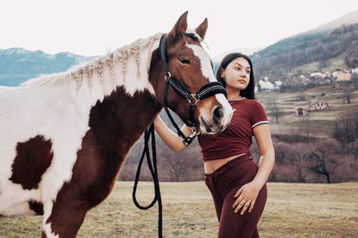 Young woman with horse standing in field