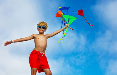 Low angle view of man with arms outstretched standing against sky