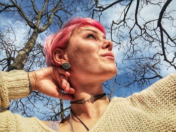 Low angle portrait of woman against bare tree