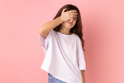 Young woman standing against pink background