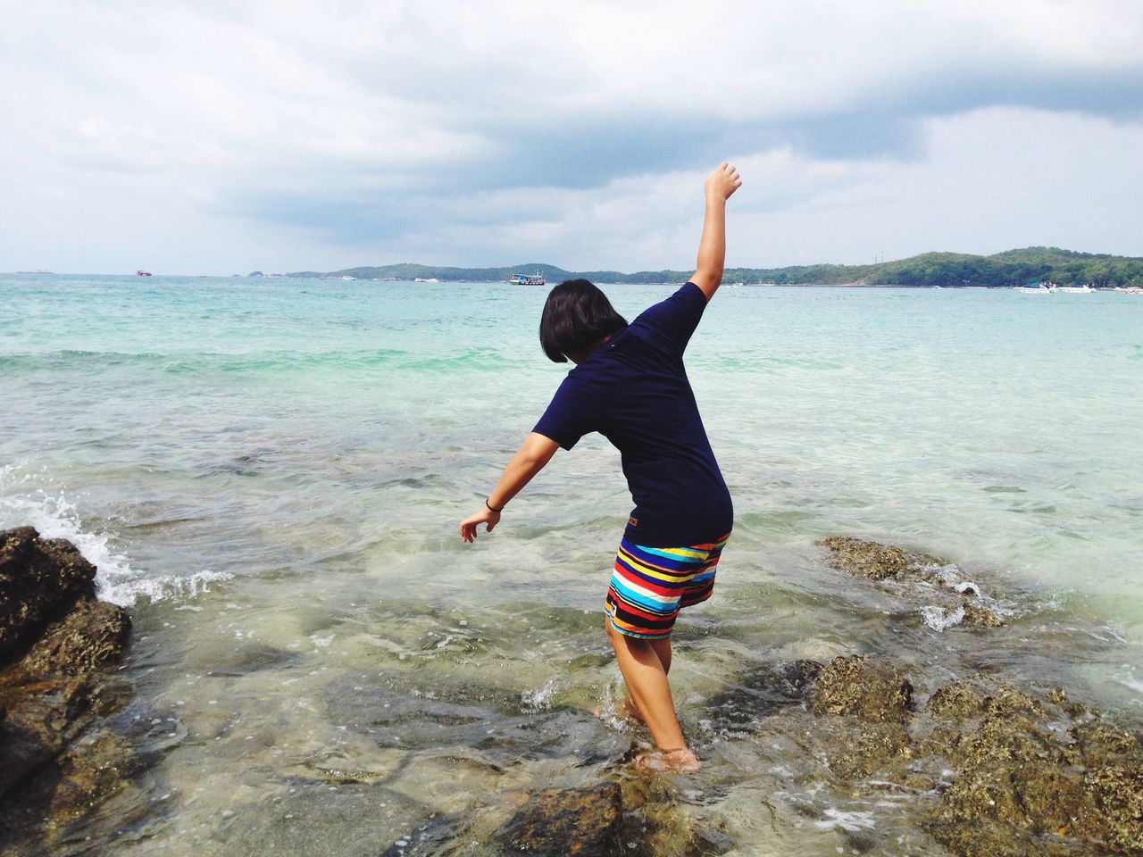 sea, excitement, jumping, full length, beach, real people, motion, horizon over water, vitality, mid-air, one person, carefree, water, outdoors, sky, rear view, leisure activity, day, happiness, cloud - sky, sand, people