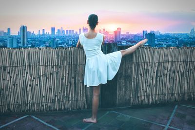 Woman stretching leg against cityscape