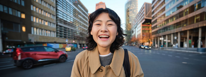 Portrait of young woman standing in city