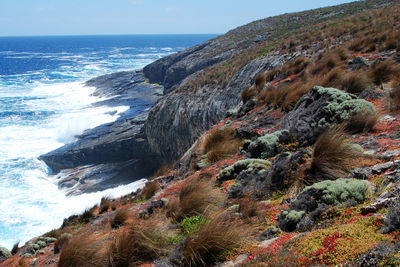 Scenic view of sea by cliff against sky