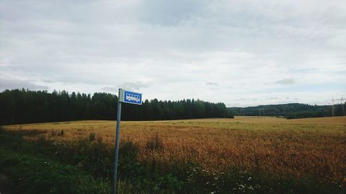 View of bus stop sign by field
