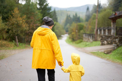 Rear view of man with umbrella standing on road