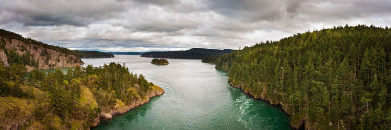 Panoramic shot of river amidst mountains against cloudy sky