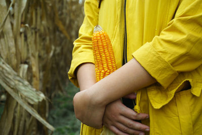 Midsection of woman holding yellow while standing outdoors