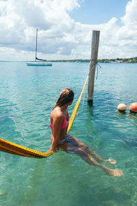 Fit woman chilling in a hammock, boat in the background. holiday concept