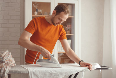 Young man looking at camera while sitting on bed at home