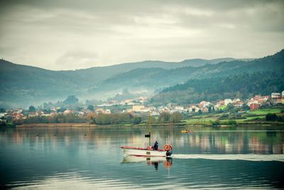 People in boat on lake against mountains