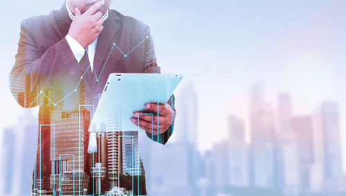 Double exposure of businessman using digital tablet and cityscape