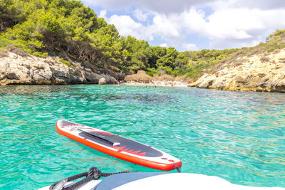 Paddle board attached to anchored boat on turquoise water