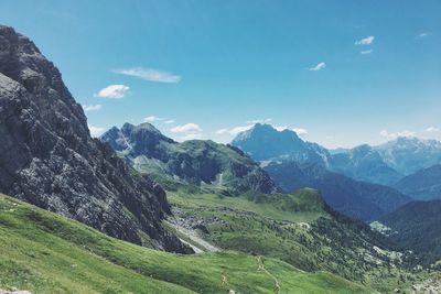 Scenic view of grassy mountains against blue sky