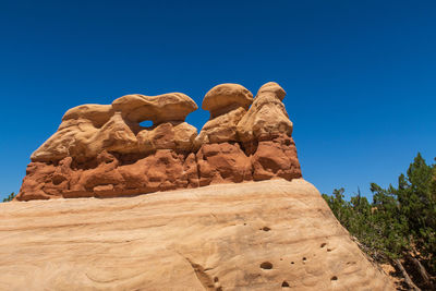 Low angle view of rock formation against clear blue sky