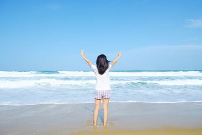 Rear view of man standing at beach against sky