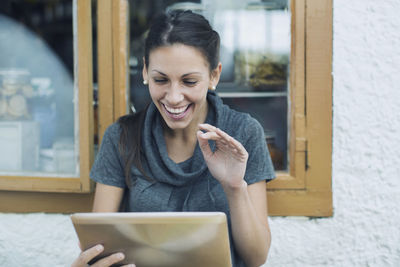 Happy woman having video chat through digital tablet in cafe