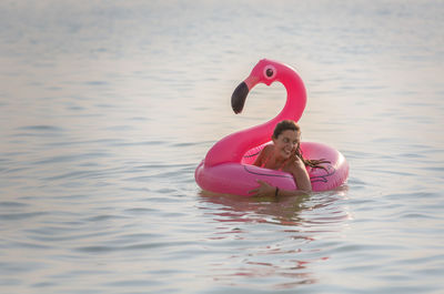 Thoughtful woman with pink flamingo inflatable ring in sea