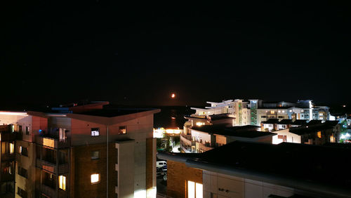 High angle view of illuminated buildings against clear sky at night