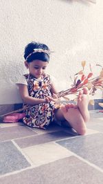 Full length of cute baby girl sitting on floor against wall